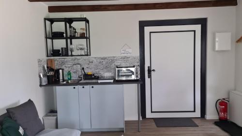 Zimmer mit einer Tür und einer Theke mit einer Mikrowelle in der Unterkunft Tiny House Südliches Friesland-FRI Natur erleben in Bockhorn