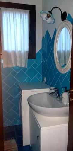 a blue tiled bathroom with a sink and a mirror at Casetta Francy in San Teodoro