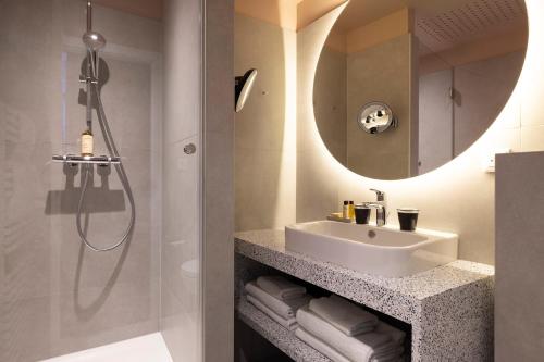 a bathroom with a sink and a shower at Hotel Le Colombier in Colmar