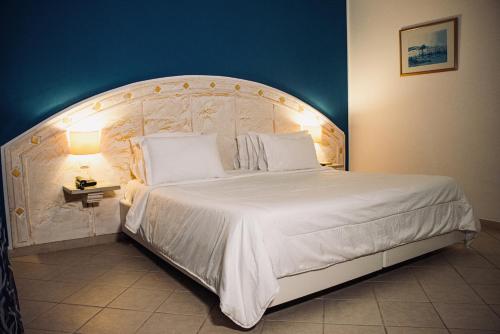 a bedroom with a large white bed with a large headboard at Cap Bon Kelibia Beach Hotel & Spa in Kelibia
