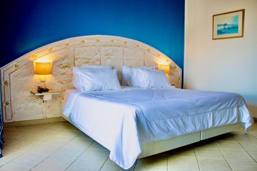 a bedroom with a large bed with a wooden headboard at Cap Bon Kelibia Beach Hotel & Spa in Kelibia