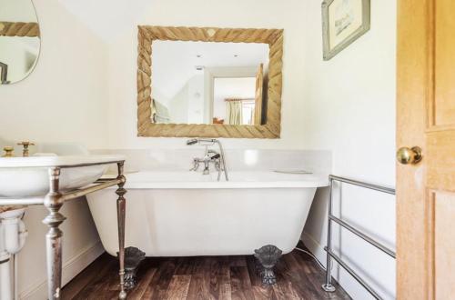a bathroom with a tub and a sink and a mirror at Cotswold Farm- Idyllic location in Stroud