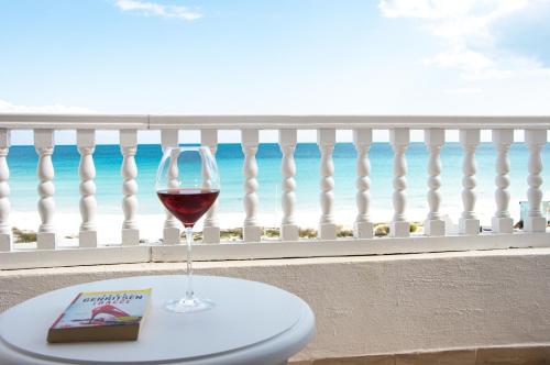a glass of wine and a book on a table on a balcony at Cap Bon Kelibia Beach Hotel & Spa in Kelibia