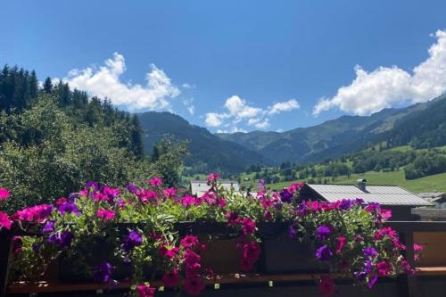 een bos bloemen op een balkon met bergen bij Mountain View Apartment in Maria Alm am Steinernen Meer