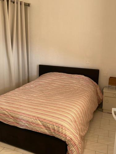 - un lit avec une couverture rayée dans une chambre dans l'établissement Charmant deux pièces aux portes de Monaco, à Cap d'Ail