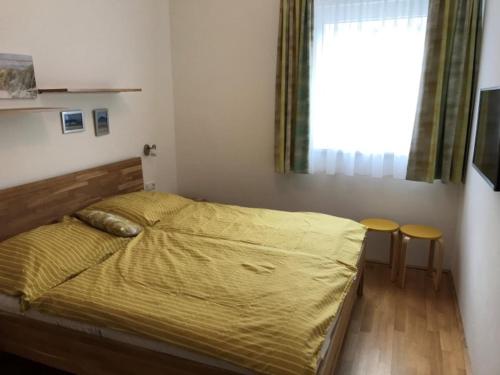 sypialnia z łóżkiem z żółtą kołdrą i oknem w obiekcie Stadtdomizil TOP 5 w Schladming