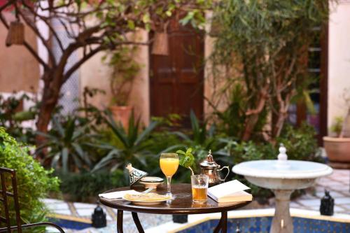 stół z dwoma kieliszkami soku pomarańczowego na nim w obiekcie Riad L'Aziza w Marakeszu