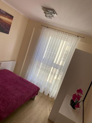 a bedroom with a purple bed and a window at Apartament przy Czarnej in Białystok