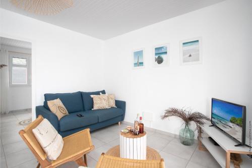 a living room with a blue couch and a tv at Villa Kaliemma in Le Marin