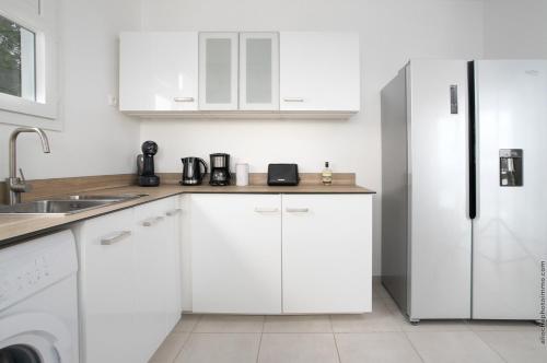 a kitchen with white cabinets and a refrigerator at Villa Kaliemma in Le Marin