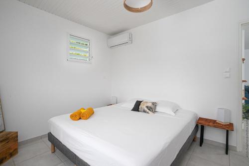 a bedroom with a white bed with two orangeippers on it at Villa Kaliemma in Le Marin