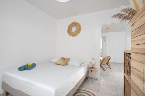 een witte slaapkamer met een bed en een stoel bij Villa Kaliemma in Le Marin