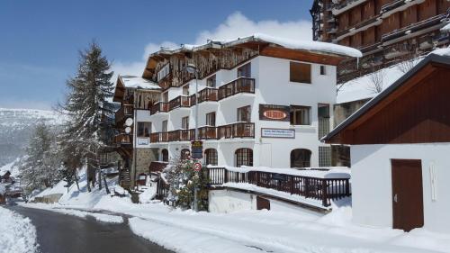 a building covered in snow next to a river at Hotel le Chamois by YourAlpAdventure in LʼHuez