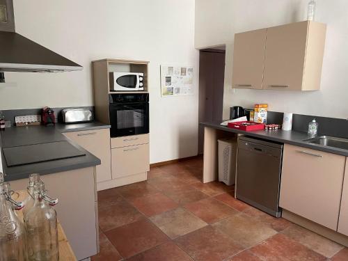 Una cocina con gabinetes blancos y encimeras negras. en Villa Tamaris, en La Seyne-sur-Mer