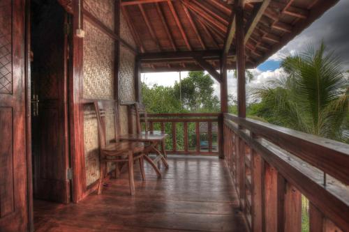 a porch of a house with a table and chairs at Bello Bungalow in Batukliang