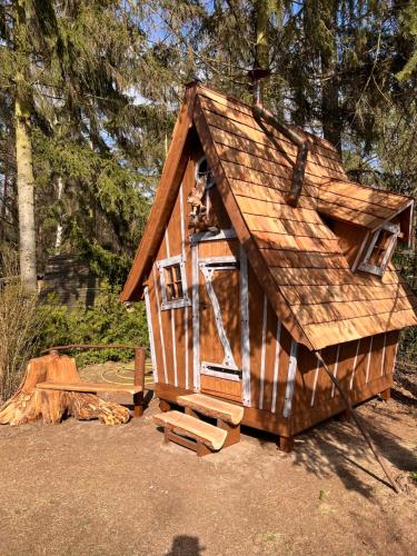 uma pequena casa de jogos de madeira com telhado em Märchenhütte- Campen am Wald und See em Neuruppin