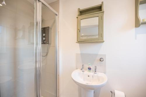 a white bathroom with a sink and a shower at Candy Cottage Halesworth Air Manage Suffolk in Halesworth