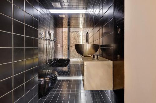 een zwart betegelde badkamer met een toilet en een wastafel bij Lxfactory Terrace Lisbon Loft in Lissabon