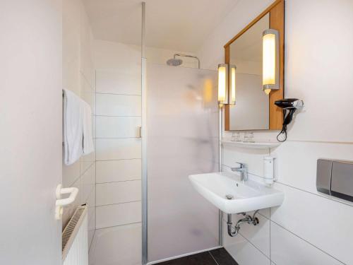 a white bathroom with a sink and a shower at ibis Kassel Melsungen in Melsungen