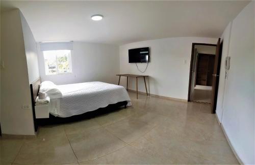 1 dormitorio con 1 cama y TV en la pared en HERSUA HOTEL BOUTIQUE, en Duitama