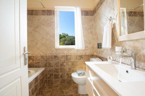 un bagno con lavandino, WC e finestra di Villa Belvedere Rosa a Tsoukalades