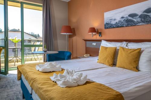 Una habitación de hotel con una cama con toallas. en Balneo Hotel Zsori Thermal & Wellness, en Mezőkövesd