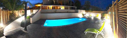 uma piscina em frente a uma casa à noite em RESIDENCE COCO em Sainte-Anne