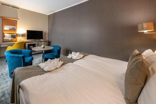 a hotel room with a bed and a table and chairs at Balneo Hotel Zsori Thermal & Wellness in Mezőkövesd