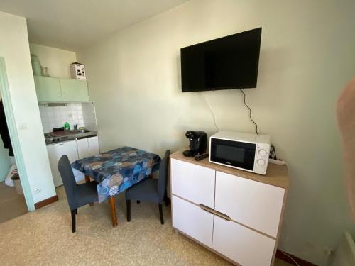 a small room with a microwave and a table with a chair at Les studios meublés de la résidence Beatrice in Bourbonne-les-Bains