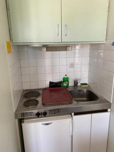 a small kitchen with a sink and a stove at Les studios meublés de la résidence Beatrice in Bourbonne-les-Bains