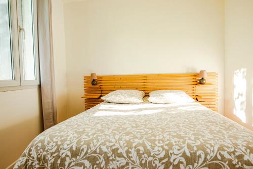 a bedroom with a bed with a wooden headboard at LA PIVOINE in Vauvert