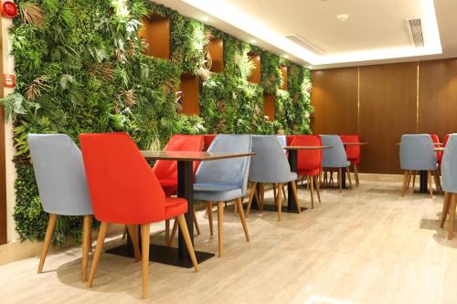 a restaurant with a green wall with tables and chairs at Roots Hotel in Makkah