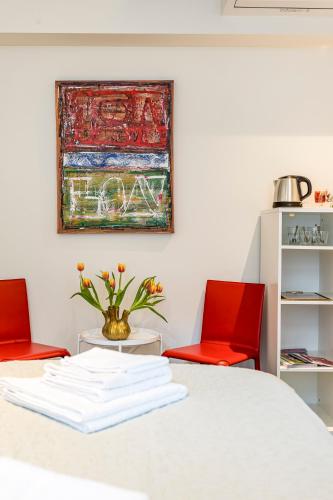 a white table with two red chairs and a painting at B&B Gracht 62 in Maastricht