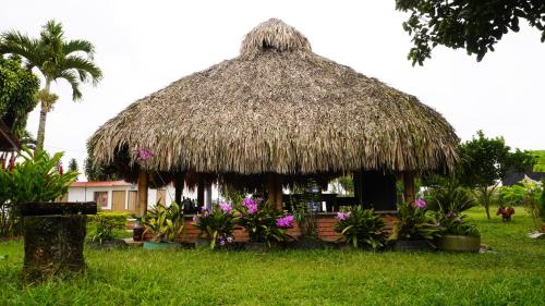 a hut with a grass roof with flowers and plants at Hostal De Paris in Pueblo Tapao