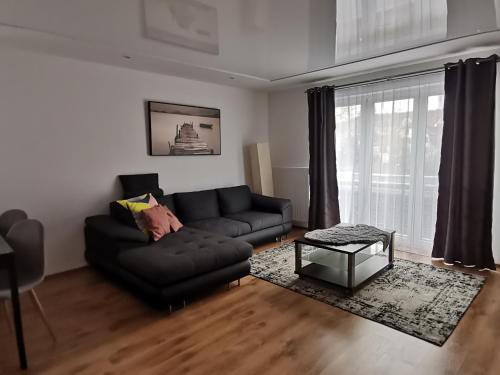 a living room with a black couch and a table at Ferienwohnung mit Aussicht auf die Burg in Wertheim