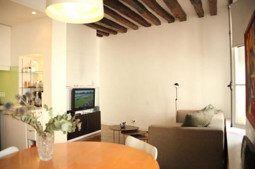 sala de estar con mesa y TV en Sèvres-Raspail Paris 6 apartment, en París