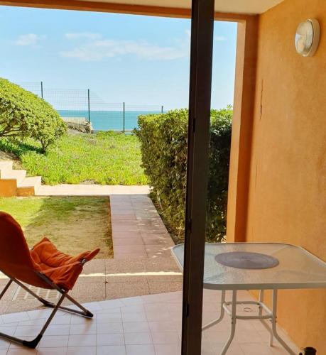 a patio with a glass table and a chair and the ocean at Cosy T2 refait à neuf climatisé, vue mer avec terrasse et jardin, Wifi piscine tennis et parking in Sète