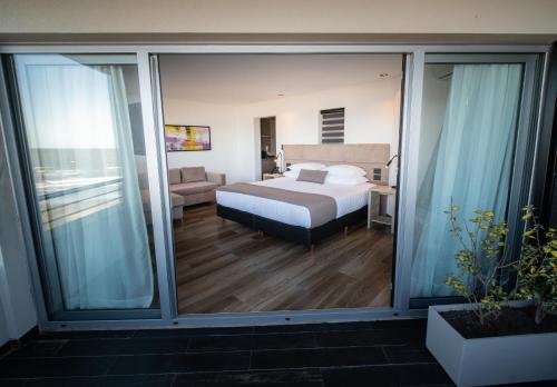 Schlafzimmer mit einem Bett und Glasschiebetüren in der Unterkunft Neco Boutique Hotel in San Bernardo