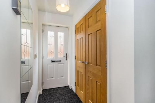 a hallway with a white door and wooden cabinets at Mayfair in Wigan