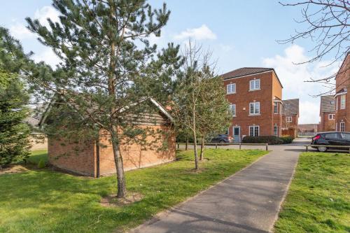 a tree in the grass next to a brick building at Mayfair in Wigan