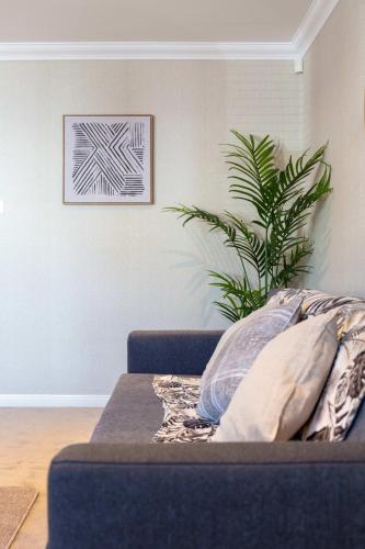 a blue couch in a living room with a plant at London Gate No1 - Donnini Apartments in Kilmarnock