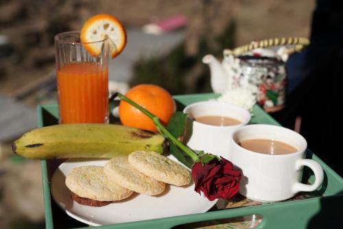 a tray with a banana and two cups of coffee at Hotel Alpine Musk in Kanatal