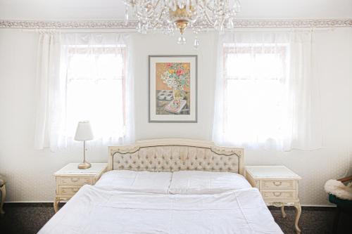 a white bedroom with a bed and two windows at Stáj Newport in Dolní Domaslavice