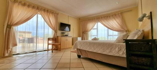 1 dormitorio con 1 cama y 2 ventanas grandes en Asda guesthouse en Mogwase