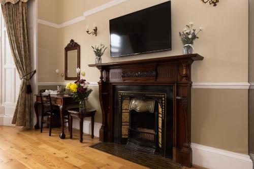 a living room with a fireplace with a television above it at The Haymarket Hotel in Edinburgh