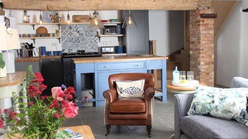 a living room with a chair and a kitchen at Courtyard Cottage at Stepps House in Ilminster