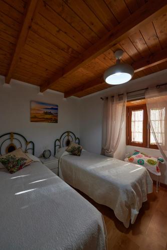 a bedroom with two beds and a wooden ceiling at Casa Rural alto prado in Isora