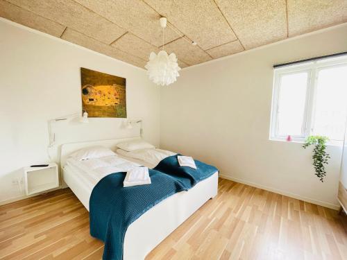 a white bedroom with a bed and a chandelier at aday - Nice and cozy place in Aalborg