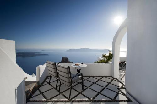 a balcony with a table and chairs overlooking the ocean at Vallais Villa in Imerovigli