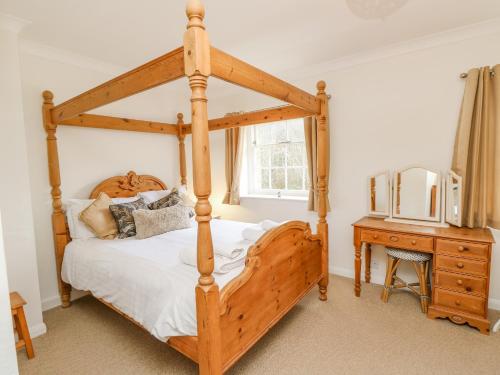 Un dormitorio con una cama con dosel de madera y una mesa. en The Coach House, en Ventnor